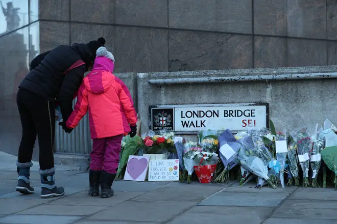Passers-by stop to look at flowers left at London Bridge in central London, following the terror attack on Friday.