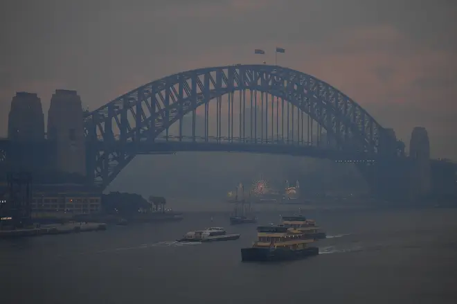 Commuter ferries sail past the Sydney Harbour Bridge as smoke haze from bushfires in New South Wales