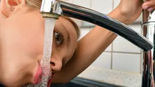 A woman drinking water from the tap