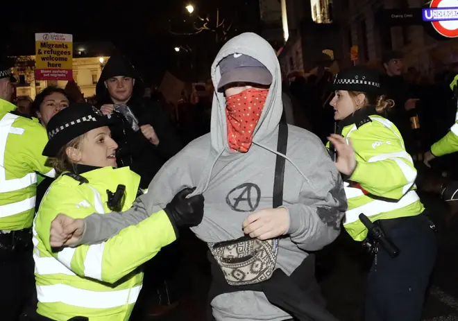 One person with his face covered is accosted by police officers