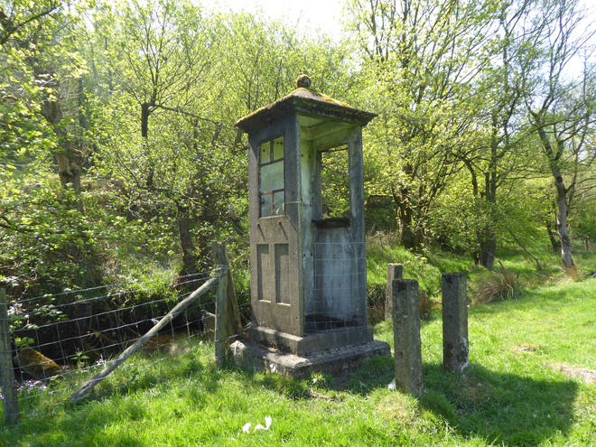 K1 telephone kiosk alongside the weir at Dean Beck in a field at Newsholme Dean in West Yorkshire,