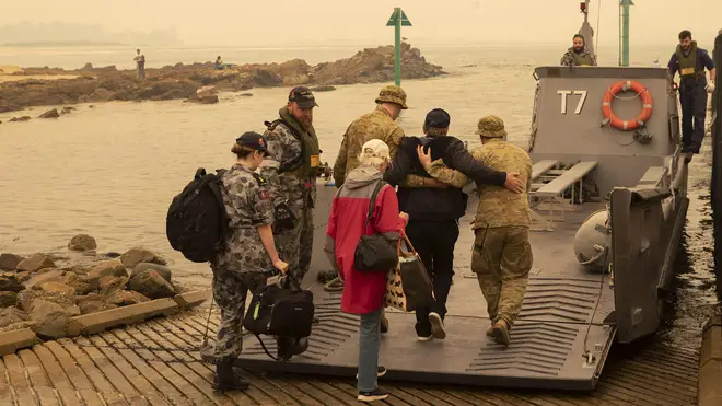 Residents board a landing craft as evacuations take place across coastal regions