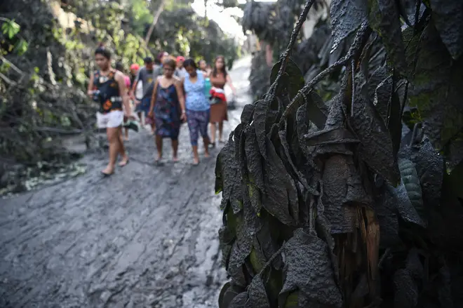 Residents walk along a muddied road after Taal volcano began spewing ash over Tanauan town