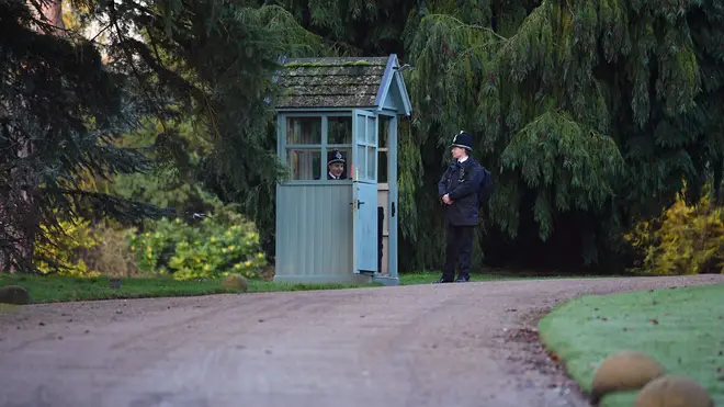 Police stand guard today at the entrance to the Queen's Sandringham estate