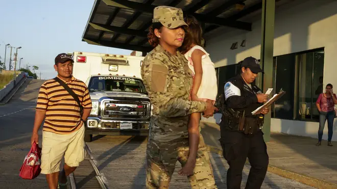 Jose Gonzalez, left, follows his 5-year-old daughter, carried by a police officer, as they leave a hospital in Santiago, Panama,