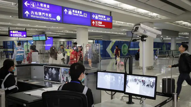 An official uses a temperature scanner to monitor passengers arriving at Hong Kong International airport in Hong Kong