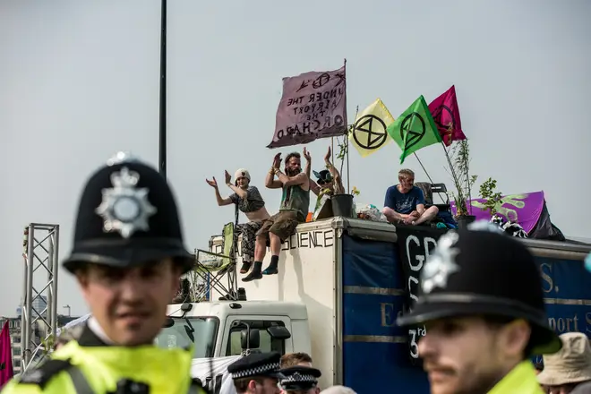 Police stand and watch as Extinction Rebellion protesters block a road in London