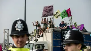 Police stand and watch as Extinction Rebellion protesters block a road in London