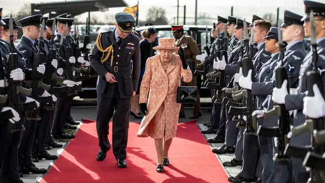Queen Elizabeth II is escorted past an RAF guard of honour as she arrives for a visit to Royal Air Force Marham