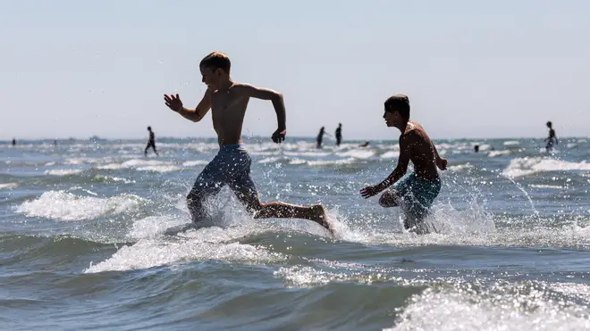 Two boys play in the sea during the hot weather