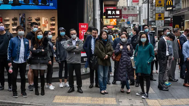 Pedestrians wearing face masks wait at a traffic light in Central district, Hong Kong