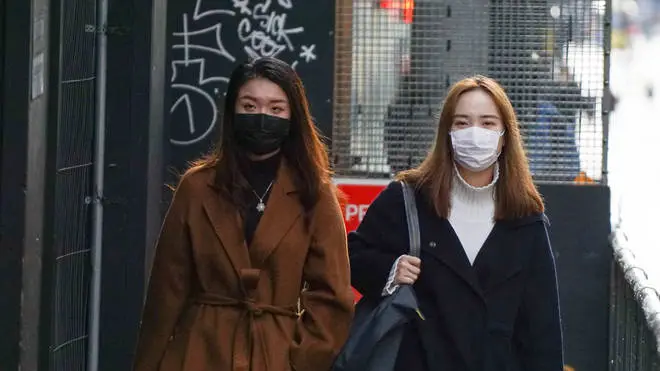 Two women wear face masks in a street in Manchester