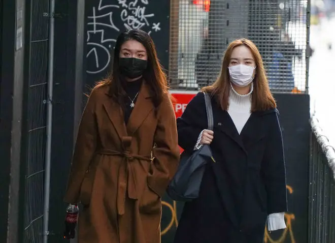 Two women wear face masks on a street in Manchester