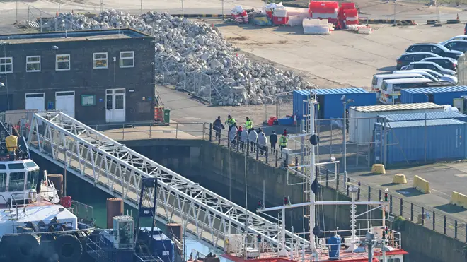 A group is led by authorities after being brought on shore at Dover