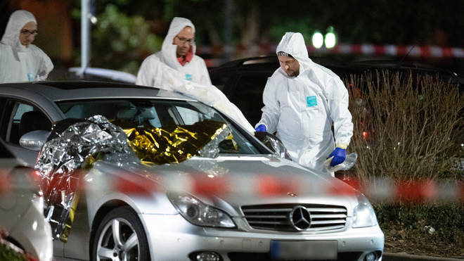 Forensic officers work on a vehicle near the scene