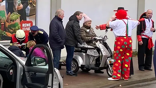 Carnival revellers stand at the site where a car drove into the carnival procession