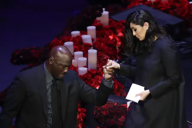 Vanessa is helped down from the stage by Michael Jordan