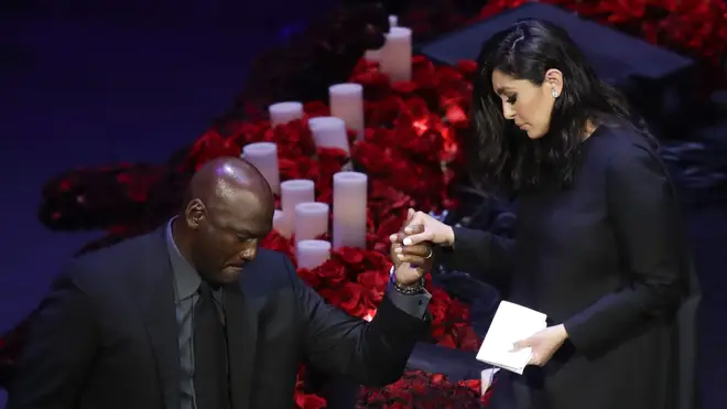 Vanessa is helped down from the stage by Michael Jordan