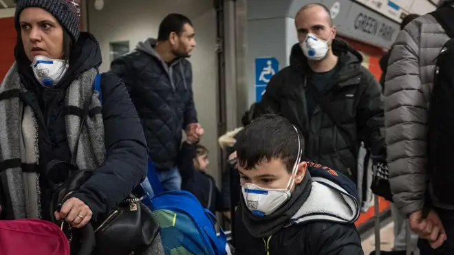 People are seen on a tube wearing face masks