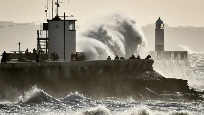 People watch as huge waves hit the sea wall in Porthcawl, South Wales