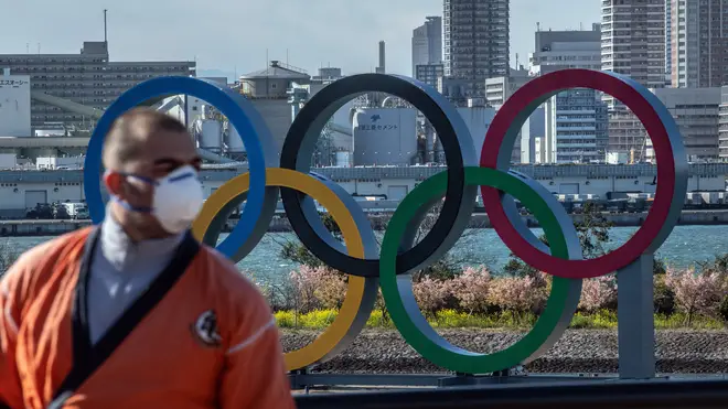 A man wearing a face mask walks near the Olympic Rings in Odaiba on March 5, 2020 in Tokyo, Japan