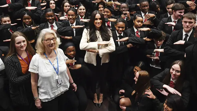 Meghan makes the "equality" sign with schoolchilren
