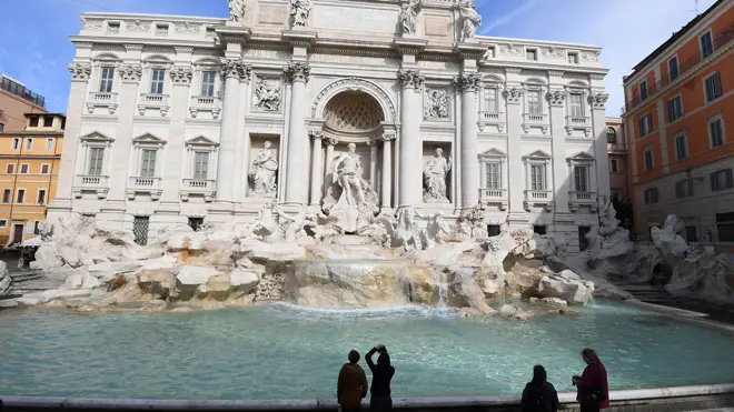 People take photos at the almost deserted Trevi fountain in Rome