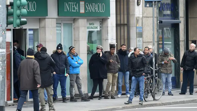 People wait in a queue outside a bank in Milan