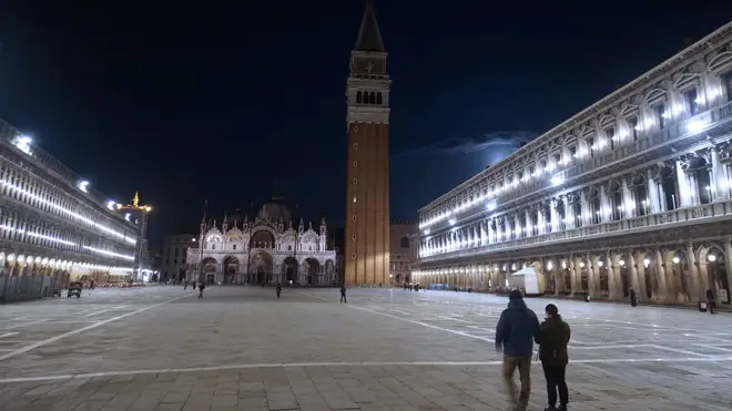 People walk in an almost empty St. Mark's Square in Venice