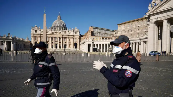 Police officers wearing masks patrol an empty St. Peter's Square at the Vatican