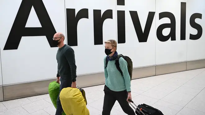 Passengers wear face masks as they arrive with their luggage at Terminal 4 of London Heathrow Airport in west London