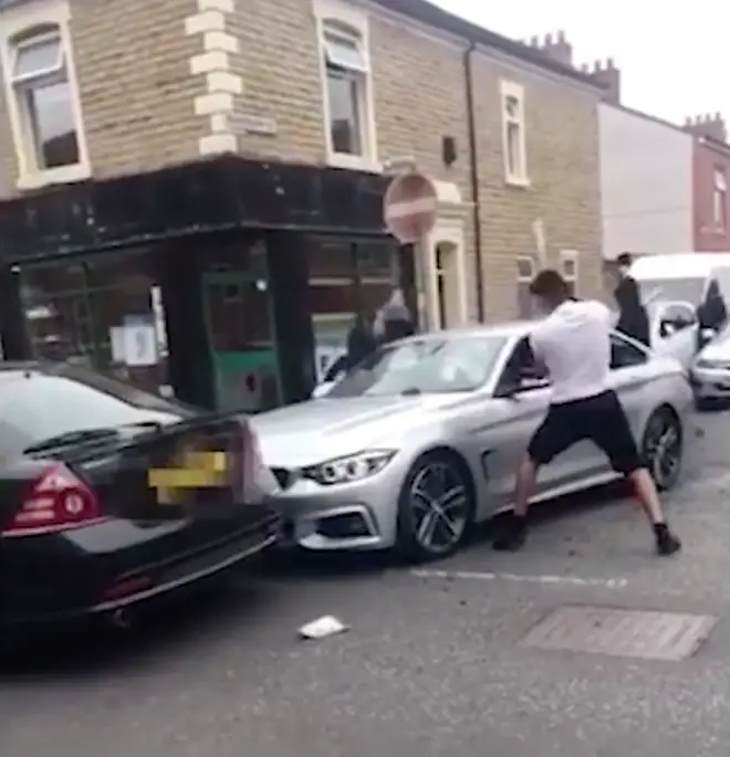 A group of men attack a BMW on a residential street