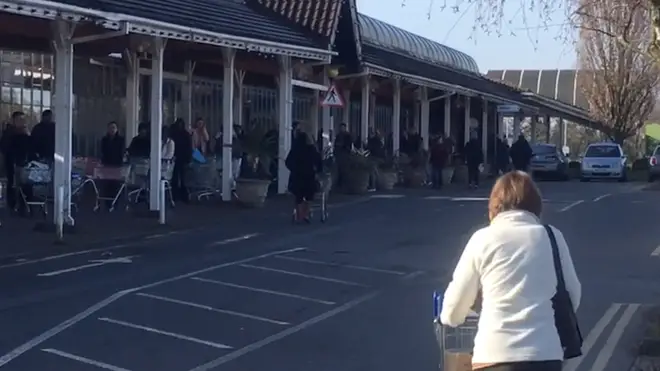 People queue out the shop at Shirley, West Mids, as they rush to buy food