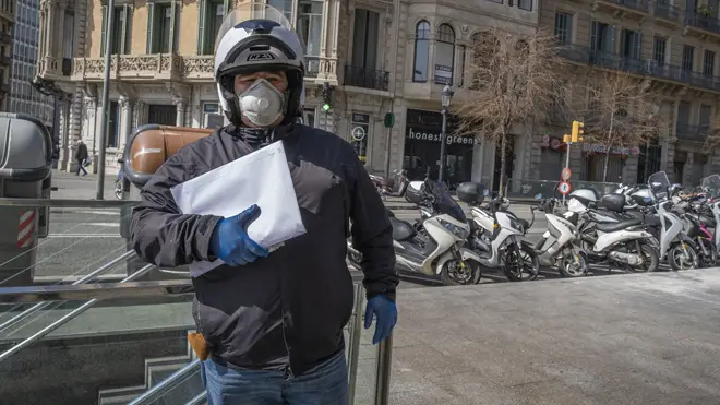 A delivery courier is seen wearing a mask in locked down Barcelona