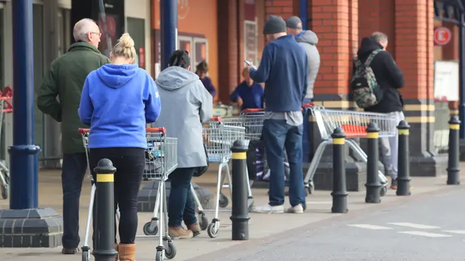 People queue 2 metres apart outside a supermarket