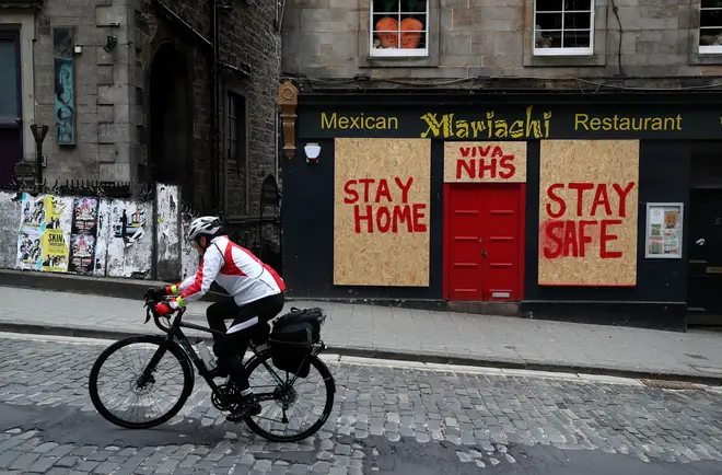 A man cycles past a boarded up restaurant in Edinburgh