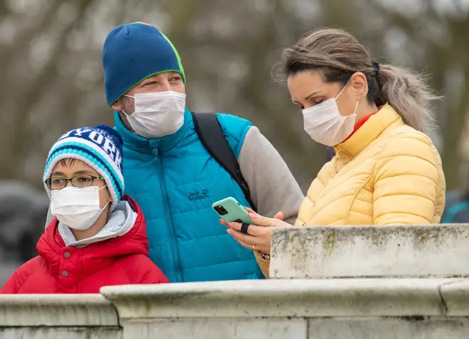 A family wear facemasks outside Buckingham Palace