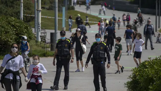 Catalan police officers patrol as families with their children walk along a boulevard in Barcelona