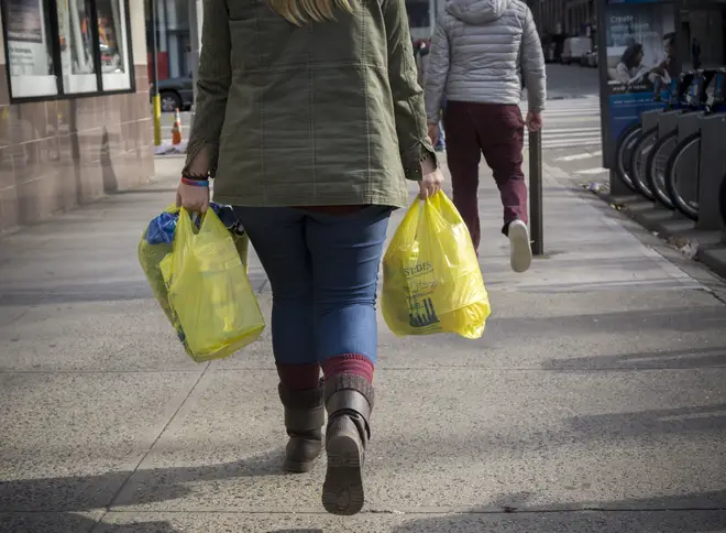 A shopper carries plastic bags
