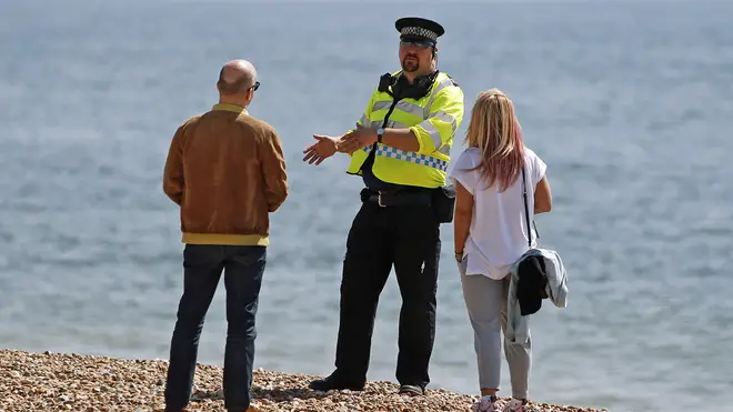 A police officer talks to a man and woman on Brighton beach