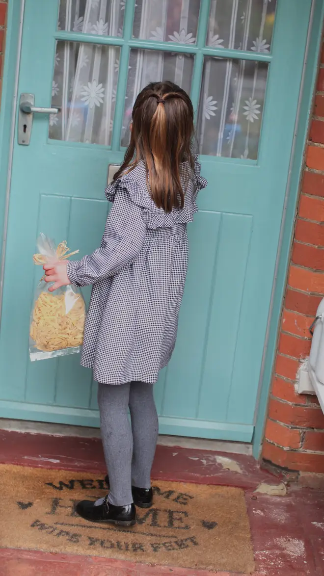 Charlotte knocks on the door of an elderly resident as she holds a bag of fresh pasta