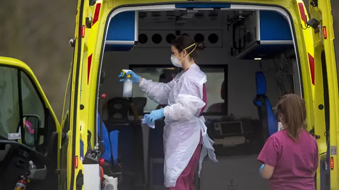 A London Ambulance worker wearing PPE cleans an ambulance after a patient is brought into St Thomas' Hospital in London