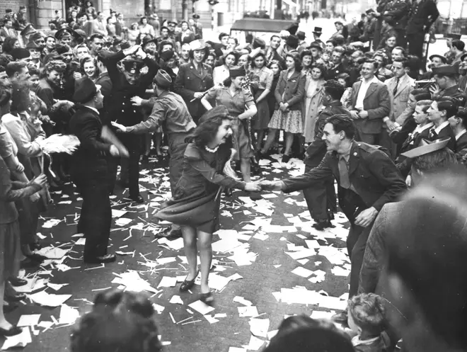 British girls, of the Picture Division of the London Office of War Information, dance in the street with American soldiers during the V-E Day celebrations