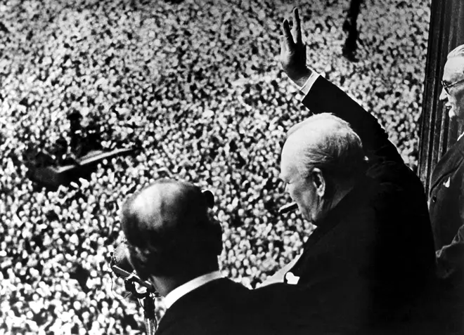 Winston Churchill gives his famous 'victory' salute a crowd of 50,000 full with the spirit of VE day from the balcony of the Ministry of Health,