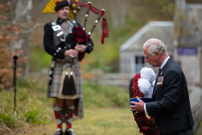Prince Charles laying a wreath for the two-minute silence as a piper plays in the background