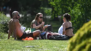 People sit in the sun in Battersea Park