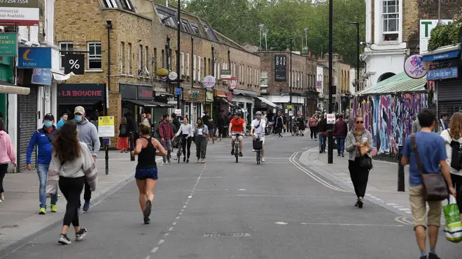 People walk and cycle through Broadway Market in London, as the UK continues in lockdown