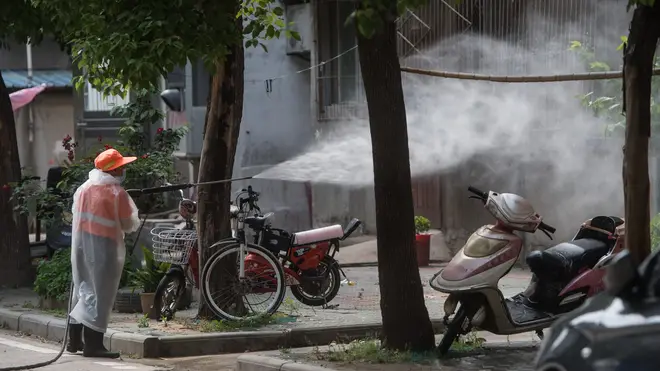 A staff member disinfects the Sanmin residential community in Dongxihu District of Wuhan