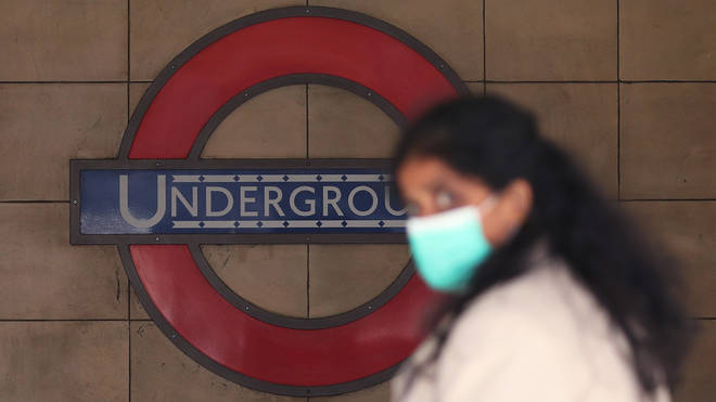 File photo: A woman wearing a face mask walks past Leicester Square Underground station