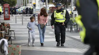 A woman and a child are escorted by a policeman at the scene of the incident